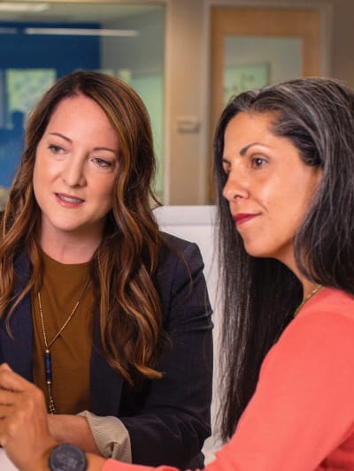 Two people sit at a computer and discuss findings.